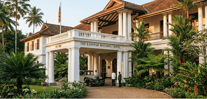 The Kandyan Mahaweli Hotel colonial entrance with vintage car and staff