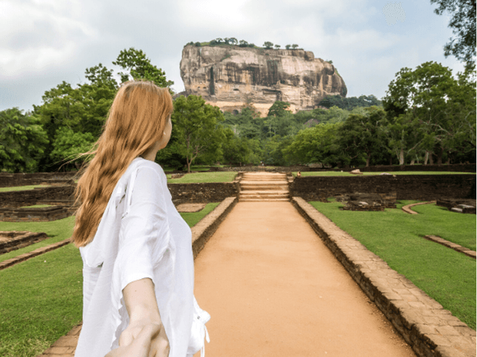 Traveller approaching Sigiriya rock fortress through lush landscape