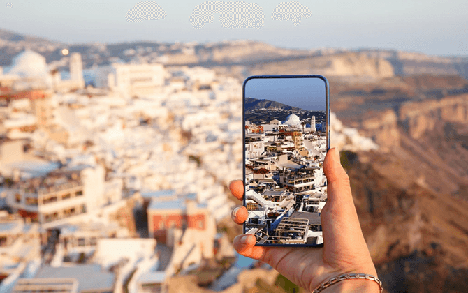 Hand holding a smartphone capturing a luxury coastal destination at sunset